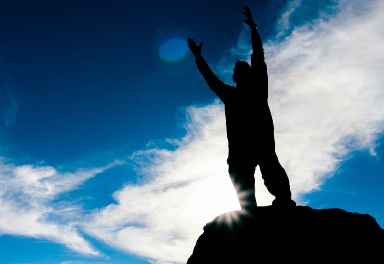 silhouette of man raising his hands under blue sky during daytime